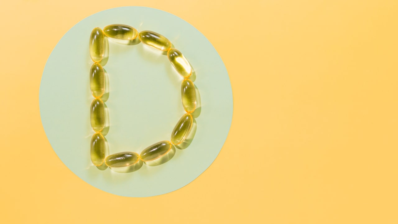 D vitamini tabletleri ile sarı bir arka plana yerleştirilmiş şekilde D harfi oluşturulmuş.