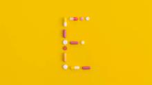 Birleşik ilaç kapsülleriyle "E" harfi oluşturulmuş bir resim. 